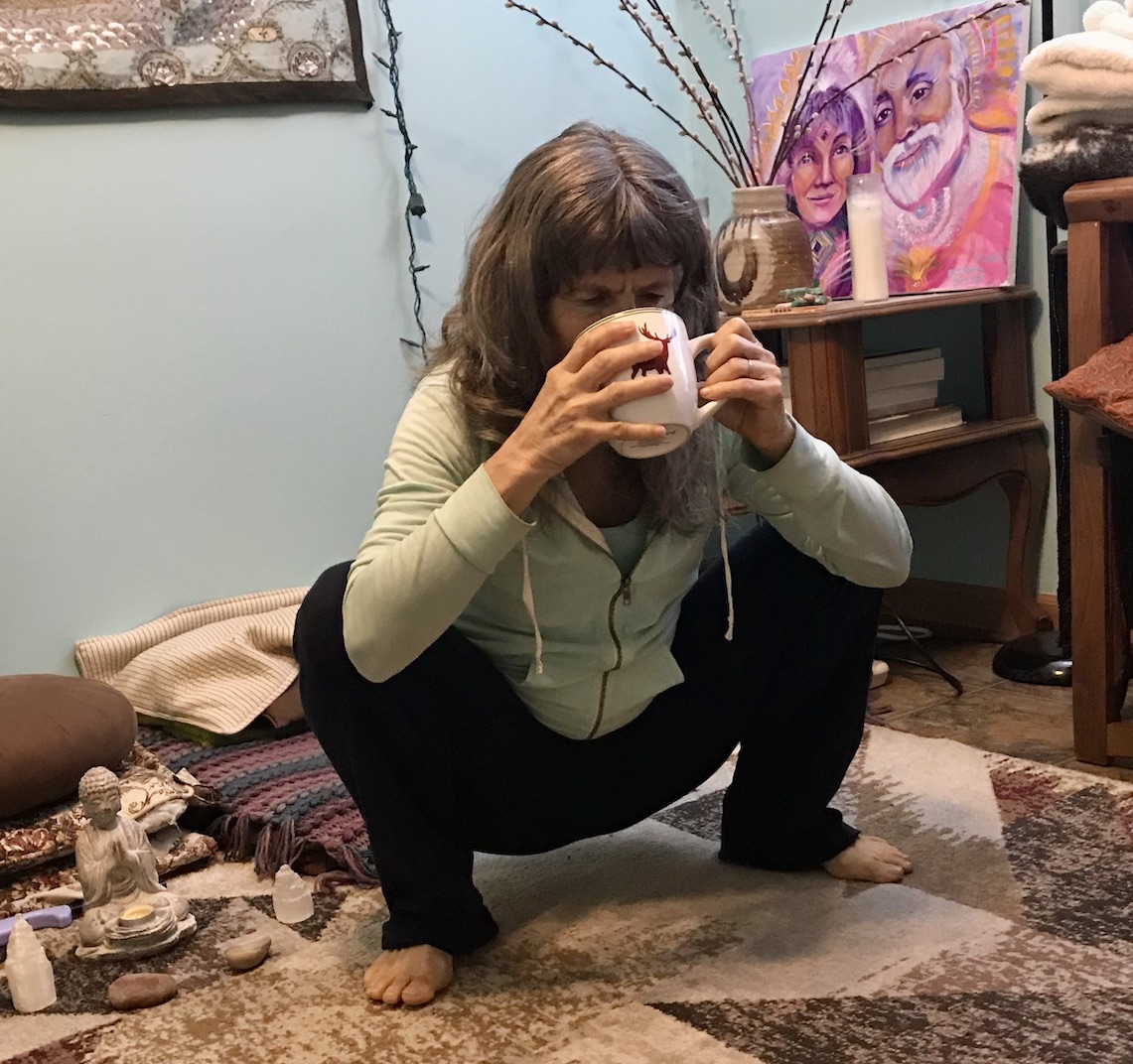 Tracy squatting while sipping heated lemon water in morning to improve digestion